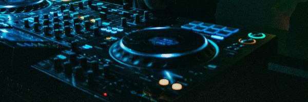 Close-up of a DJ adjusting controls on a club mixer during a live electronic music set