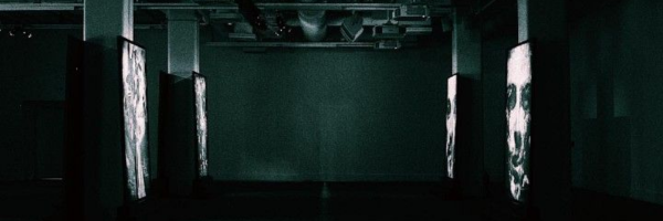 Dark underground venue with digital screens and minimal green lighting